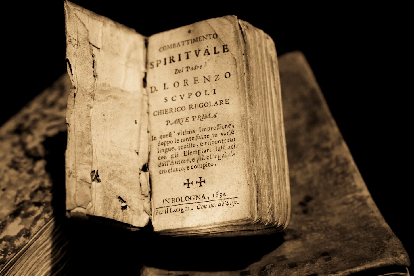 Libro antico aperto con pagine e testo consumati.